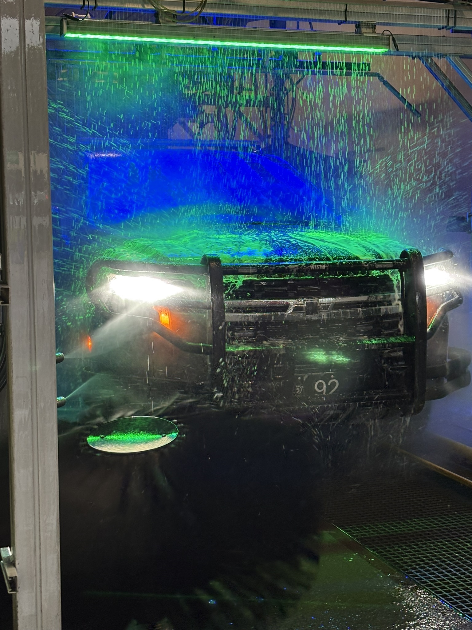 Police SUV receiving a wash under colorful LED lights