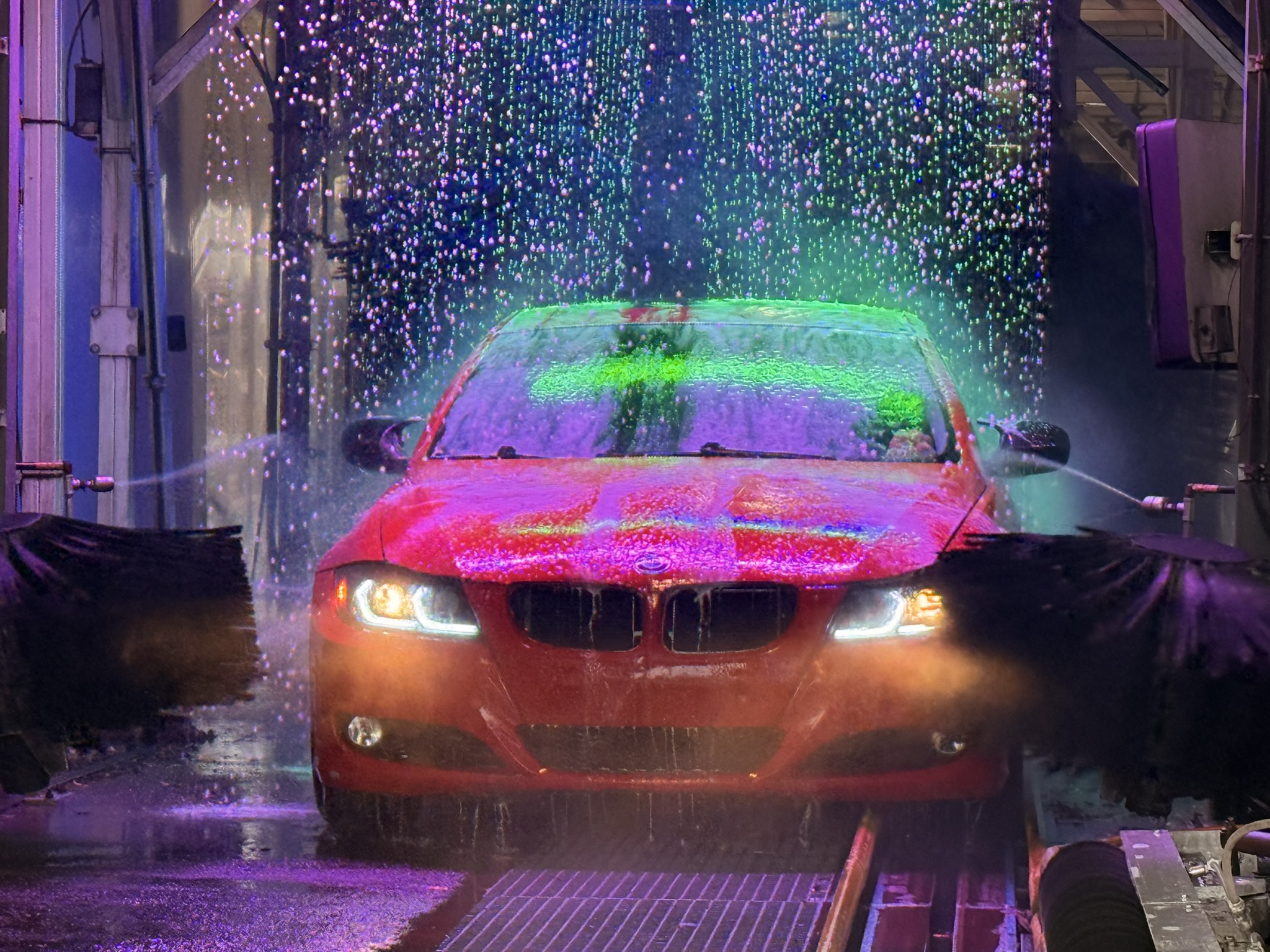 Red BMW driving through the colorful Stroll N Shine wash tunnel
